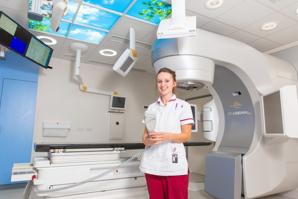 Radiotherapist with one of the centre’s Varian Truebeam Radiotherapy machines kitted with ‘Brainlab Elements’