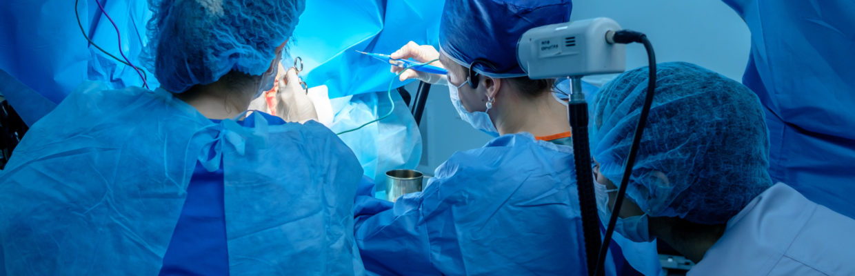 Surgeons in an operating theatre wearing blue scrubs