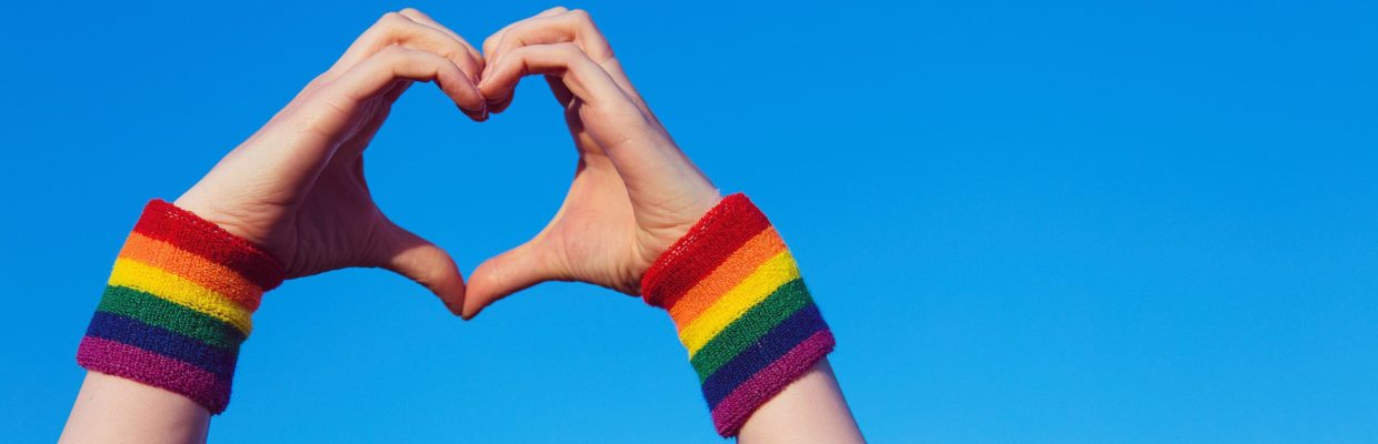 Hands in heart shape with rainbow coloured wristbands