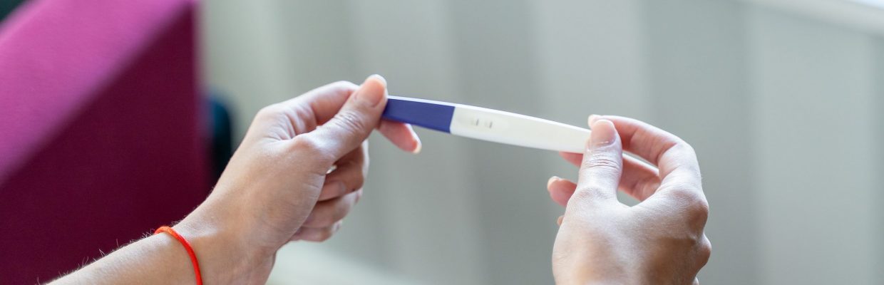 Woman holding pregnancy test awaiting result