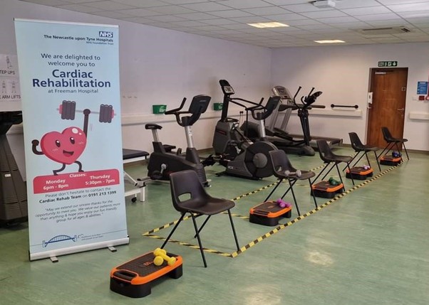 Picture of exercise equipment set up such as exercise bikes, chairs with weights and steps with a cardio rehab pull up banner at the Freeman Hospital.