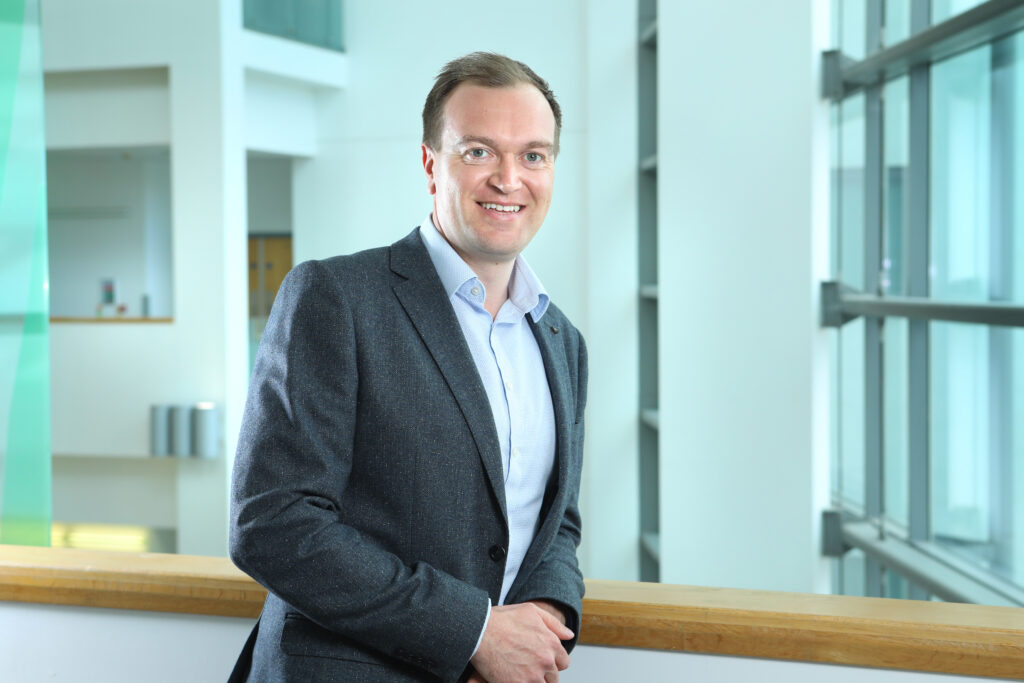 Picture of Wayne Elliott, the associate director for commercial enterprise standing in the hospital atrium.