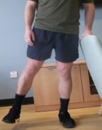 Person stood on one leg lifting the other leg sideways. They are holding onto something for support. 