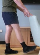 Person stood on one leg with one leg forward. They are holding onto a stable support. 