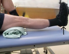 Person laid on back with one need bent and one out in front of them with a towel roll under the straight knee.