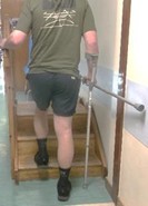 A person walking up the stairs with one crutch