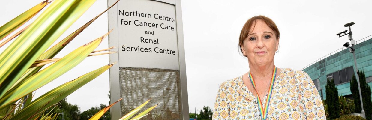 Angela Jackson standing by a sign for the Northern Centre for Cancer Care