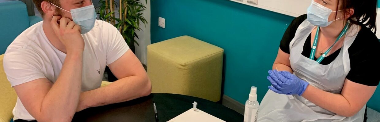 A medical professional talking to a man wearing masks