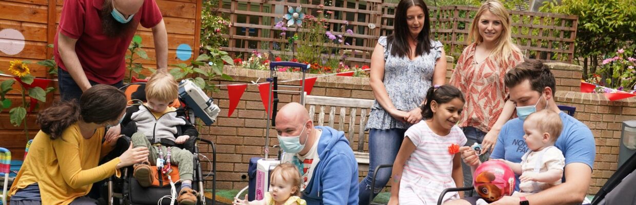 A group photo of children and adults playing outside by the hospital