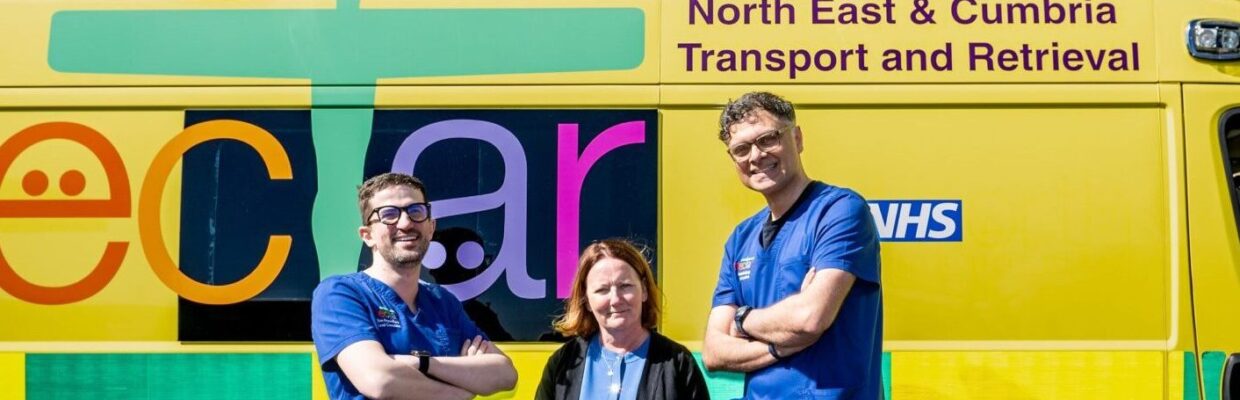 NECTAR staff in blue scrubs stood in front of yellow NECTAR ambulance