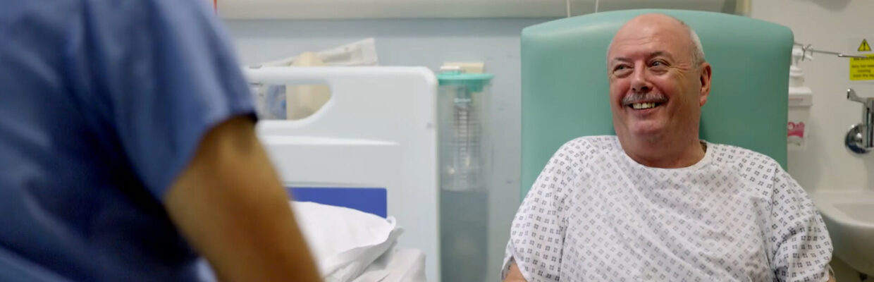 A male patient sitting in a chair next to a hospital bed