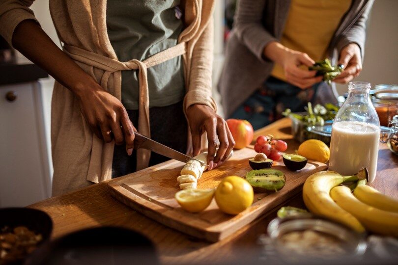 Close up of people chopping fruit and vegetable.