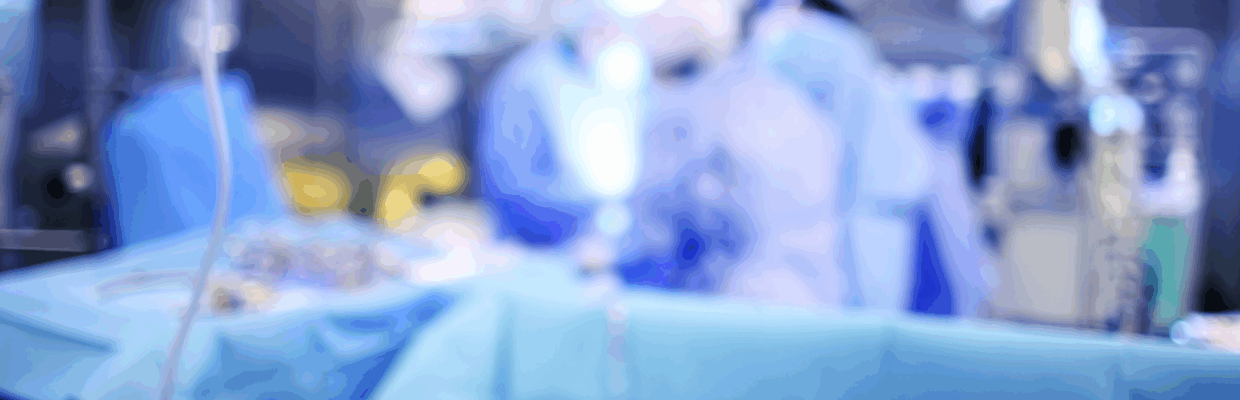 A blurry image of surgeons operating on a patient in theatre