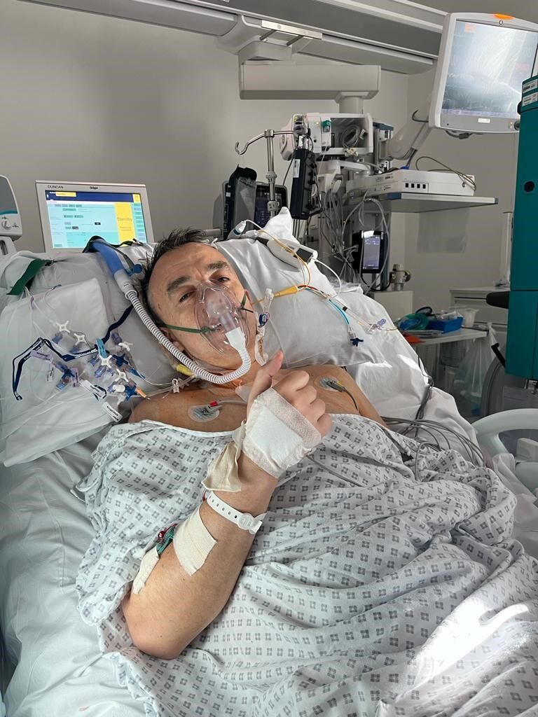 Dermot in a hospital bed hooked up to machines