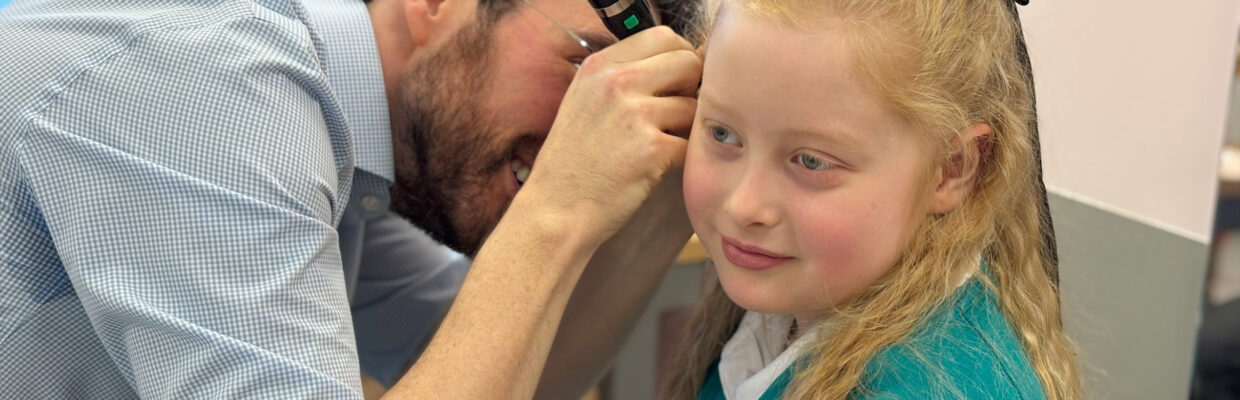 Mr Jason Powell looking inside a young girls ear