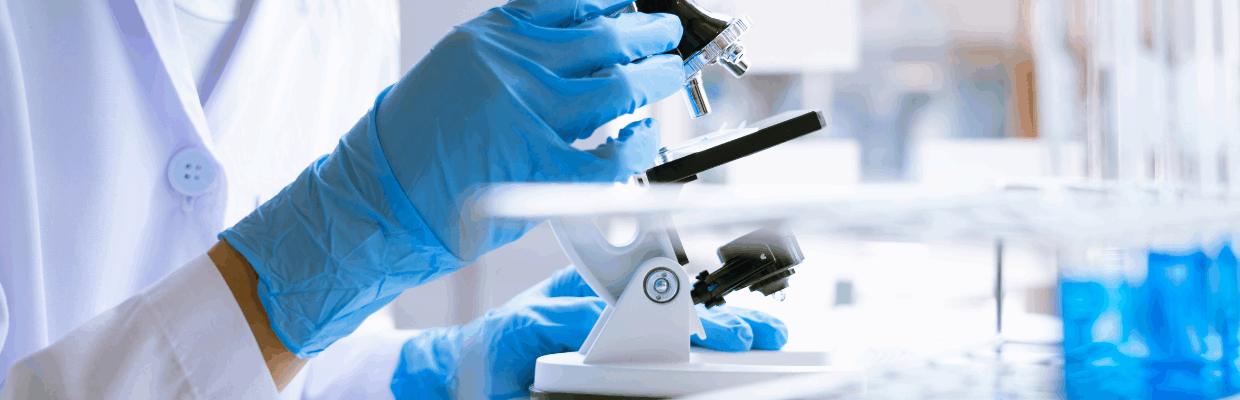A close-up photo of a scientist looking at a sample under a microscope