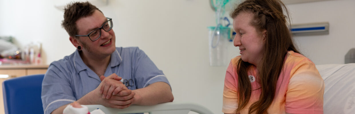 A photo of a medical professional talking to a patient who has a large cast on her leg