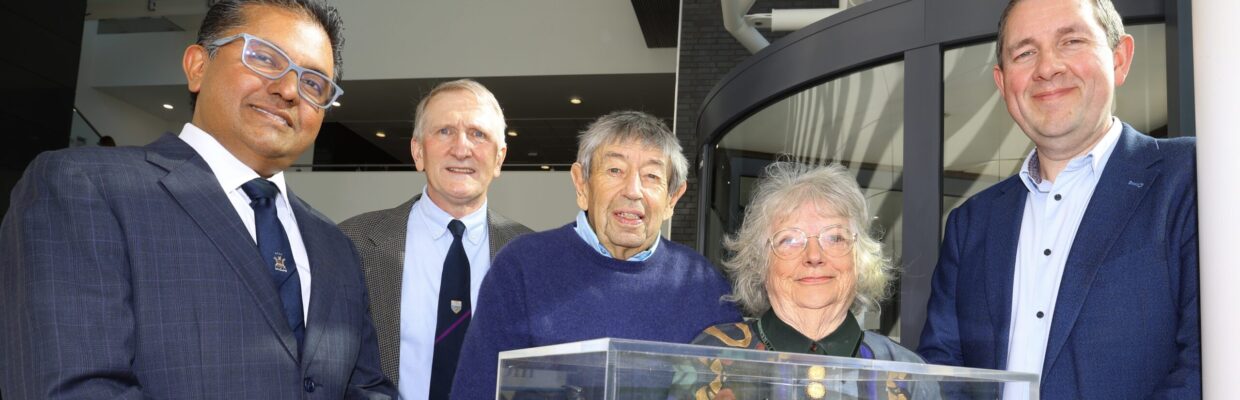 A group photo standing in front of a model of a heart in a glass box