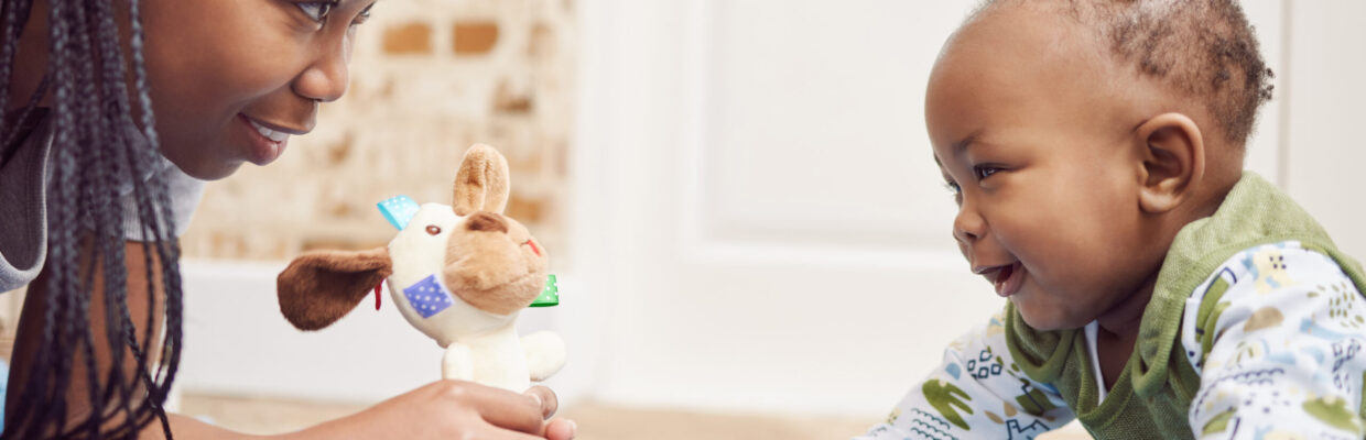 A mother holding a toy while playing with her baby