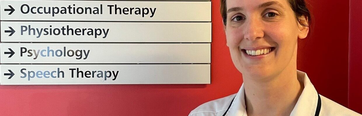 A nurse standing in front of a sign directing people to different departments