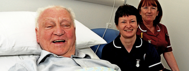 Sir Bobby Robson lies in a hospital bed with two nurses by his side,