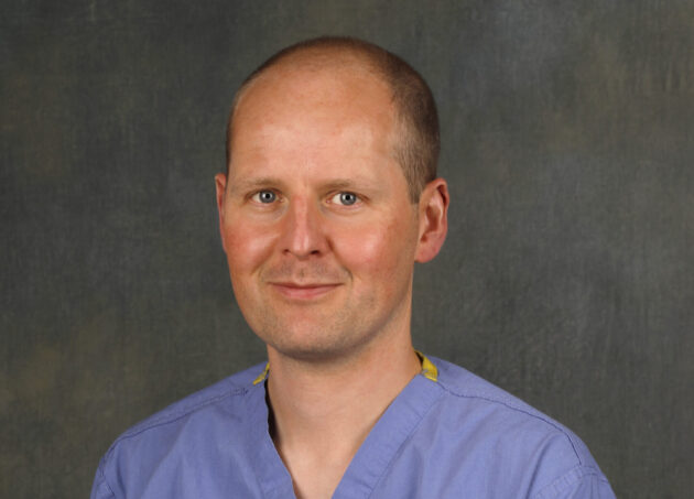A portrait of Dr. Tom Oliphant dressed in his scrubs.
