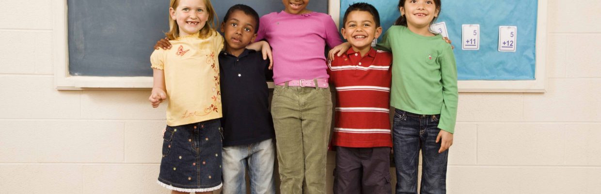 Group of diverse young students standing together in classroom. Horizontally framed shot.