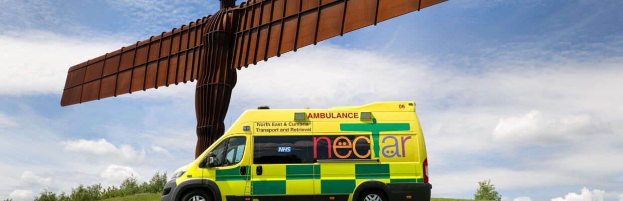 NECTAR ambulance parked on green grass with Angel of the North with blue sky.