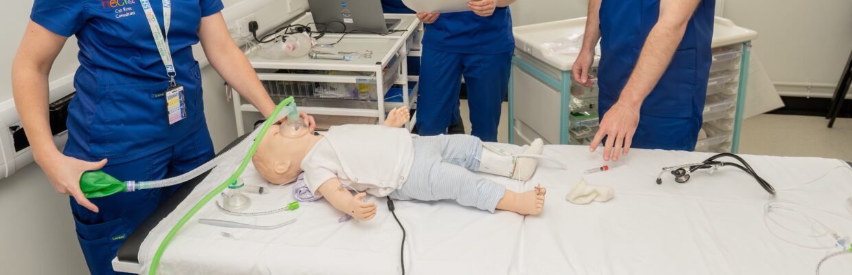 Picture of staff in blue scrubs training resuscitation on a sim doll for training