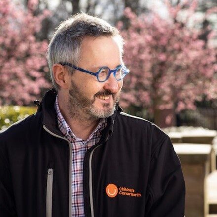 Dr Geoff Shenton standing outside with blossom trees in the background