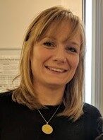 A headshot of Dr Gail Halliday wearing a black top with her hair down.