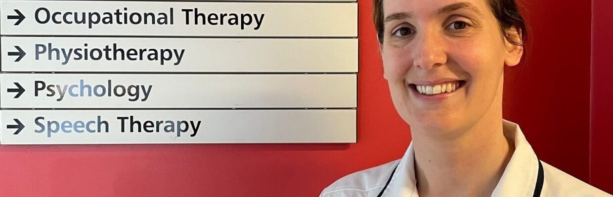 A nurse standing in front of a sign directing people to different departments