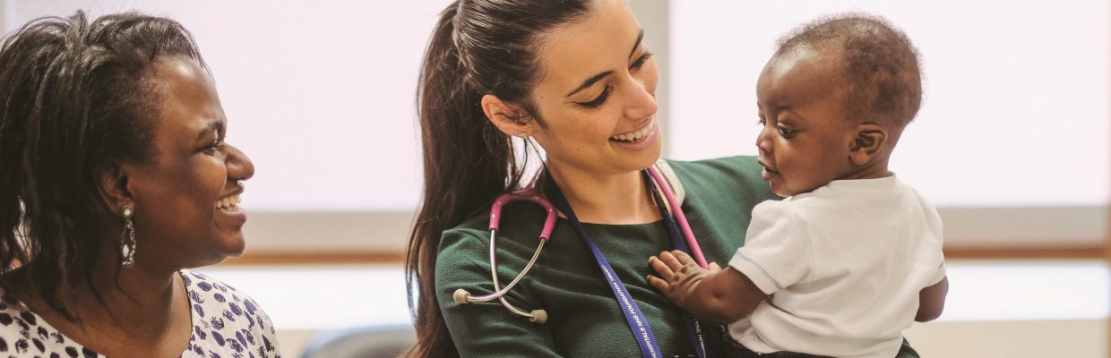 Doctor holding child with smiling mother