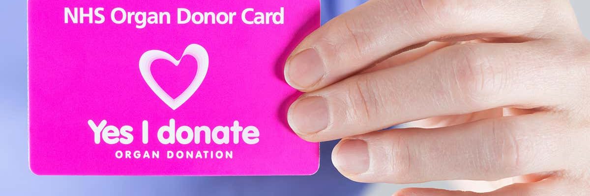 An image of someone holding a Yes I donate organ donor card
